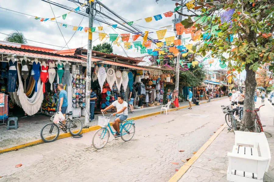 Downtown Tulum street with papel picado bunting, shops and people on bicycles